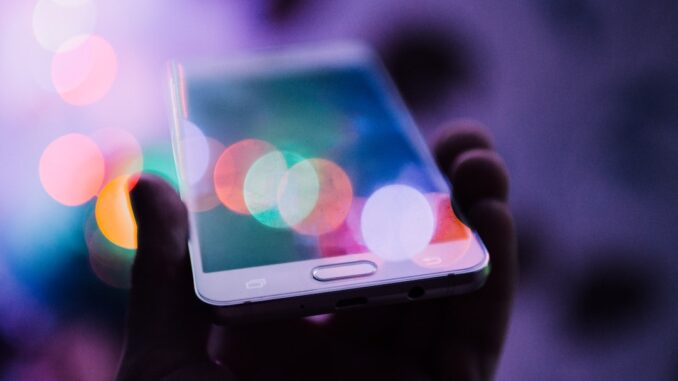 En person holder en kompakt smartphone i hånden